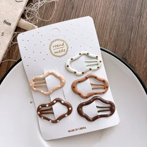 Close-up of five gradient dot patterns on wave-shaped hair clips in warm coffee tones