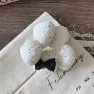 Nahaufnahme eines weißen Polka-Dot-Haargummis mit schwarzer Schleife auf Vintage-Stoff