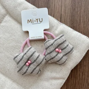 Detail of pink elastic hair ties with black and white striped star charms and pink beads