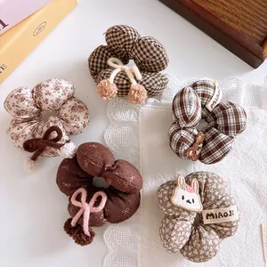 Detailed view of autumn plaid hair ties with cute bear and bow decorations in brown tones