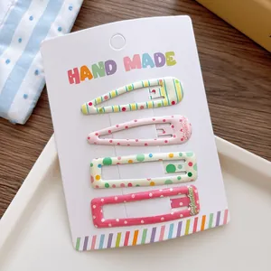 Close-up of four colorful polka dot metal snap clips for girls on display card