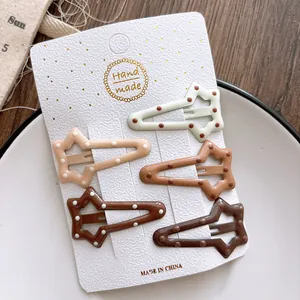 Detailed view of 5-piece set of star-shaped hair clips with mocha brown polka dot patterns