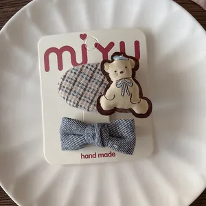 Set di fermagli per capelli per bambina con orsetto marrone e fiocco a righe blu su carta