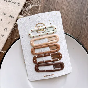 Detail view of five gradient coffee-colored polka dot hair clips for girls on display card