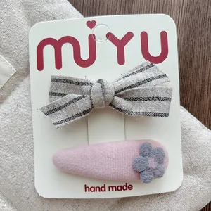 Close-up of handmade striped cotton bow and pink felt flower hair clips for girls