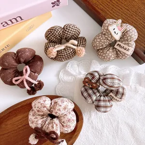 Detailed view of five autumn-style plaid and floral scrunchies with cute animal patches