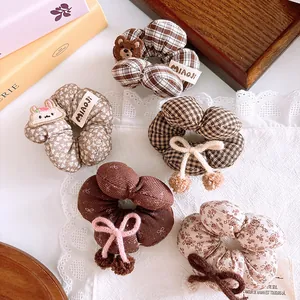 Detail view of 5-piece girls hair scrunchies in brown plaid and floral patterns