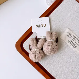 Close-up of brown plush bunny hair ties with white pearls and textured knit fabric