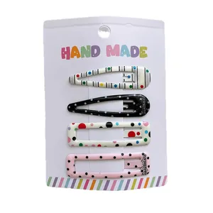 Set of 4 colorful patterned snap hair clips with polka dots and stripes on a display card