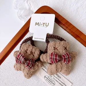 Close-up of cute gingerbread man hair ties with khaki plush and checkered bows for girls