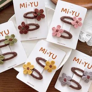 Detail of five pairs of handmade knit flower hair clips in various colors on cards