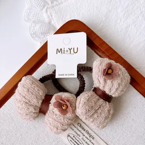 Close-up of brown elastic hair ties with beige bows and floral center on a display card