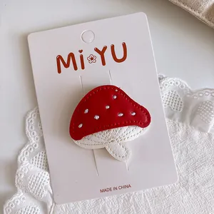 Detail of red mushroom leather hair clip with fine stitching on white lace background