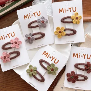 Set of five pairs of colorful knitted flower hair clips on white card packaging