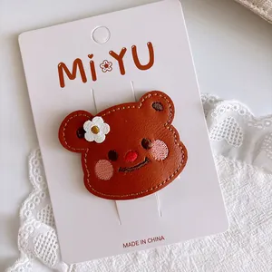 Macro detail of brown leather bear hair clip with embroidery and a small white flower