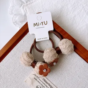 Detail of high-elasticity brown hair ties with beige checkered balls and faux pearls