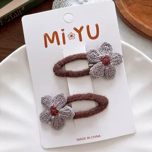Detail of two crochet flower hair clips with brown velvet coating on a card display
