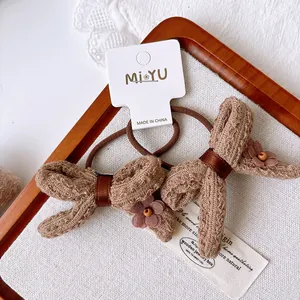 Close-up of brown knitted bow hair ties with floral accents on white paper card
