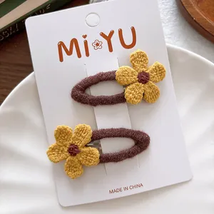 Detail of yellow knit flower and brown plush hair clips on a decorative white display tray