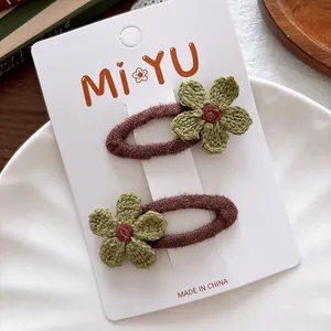 Detailed knit texture of two handmade green crochet flower hair clips on brown clips