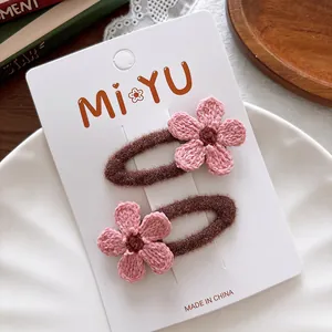 Detail of pink knitted flower hair clips on brown plush base for kids on a card
