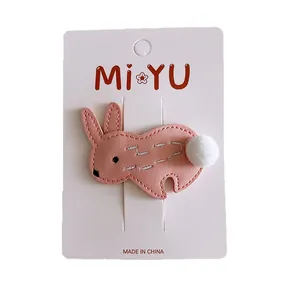 Cute pink leather rabbit hair clip for girls with a white pom-pom detail on white card