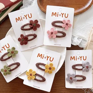 Detailed view of handmade knitted flower hair clips in vibrant colors on display cards