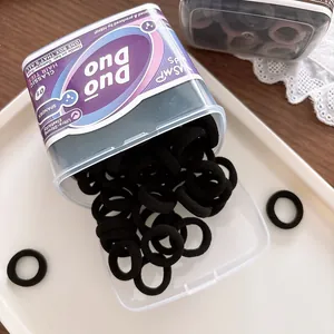 Nahaufnahme schwarzer, hochelastischer Haargummis in einer Box auf einem weißen Tablett