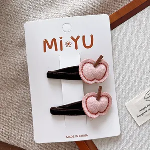 Détail de deux jolies barrettes en feutrine rose en forme de pomme avec coutures fines