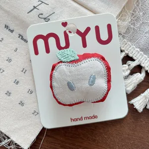 Detailed view of handmade fabric red apple hair clip with leaf on calendar backdrop