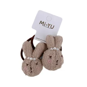 Pair of beige knitted bunny hair ties with pearl accents and brown elastic bands