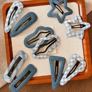 Set of blue denim and gingham hair clips in geometric shapes on a wooden tray