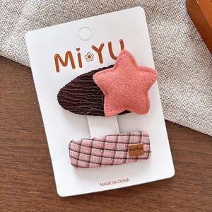 Détail de pinces à cheveux en tissu à carreaux roses et étoile marron sur carte