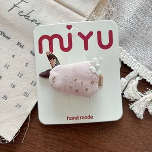 Detailed view of handmade pink fabric bunny hair clip with floral ear and pearl detail