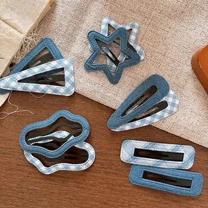 Detailed view of denim and blue gingham fabric hair clips on a rustic wooden background