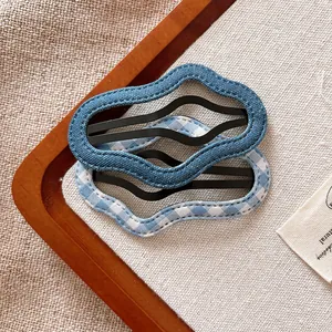 Close-up of blue fabric wave hair clips with denim and plaid patterns on wood