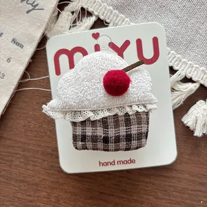 Close-up of handmade cupcake hair clip with white fleece, red cherry, and lace details