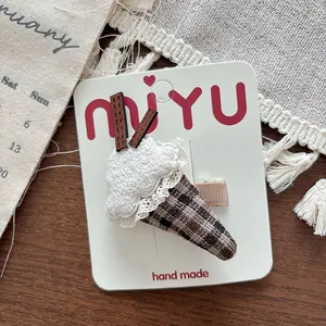 Detail of a handmade crochet ice cream hair clip with lace and plaid pattern on card