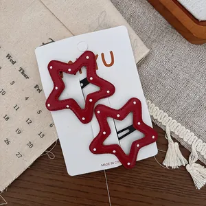 Gros plan de deux pinces à cheveux étoiles en cuir rouge à pois blancs sur carte support