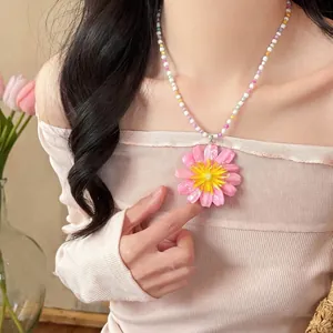 Detailed view of a colorful beaded necklace with a large pink daisy flower pendant.