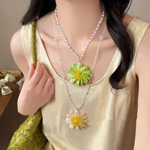 Detailed view of layered colorful flower beaded necklaces on a model wearing yellow top