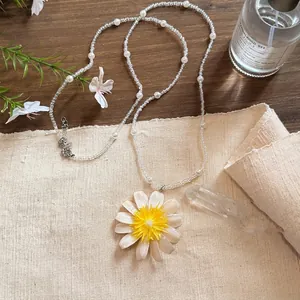 Detailed macro view of a daisy flower pendant beaded necklace on a linen fabric background