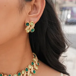 Detail view of gold-tone vintage earrings and necklace with green resin stones