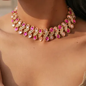 Close-up detail of vintage palatial style gold necklace with pink resin and rhinestones.