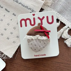 Detail of handmade acorn hair clip featuring corduroy fabric and a red ribbon bow
