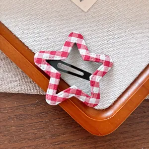 Gros plan d'une pince à cheveux en forme d'étoile avec motif vichy rouge et blanc