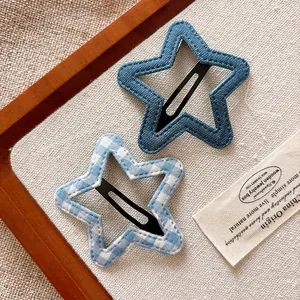 Detail of star-shaped denim blue and checkered hair clips on a soft canvas background