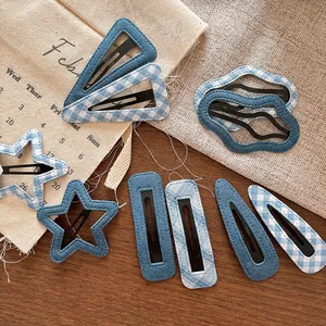 Detail of denim and blue checkered fabric hair clips with visible stitching on wood