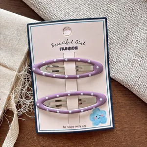 Dettaglio di due fermagli per capelli ovali viola a pois su una scheda decorativa rosa