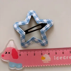 Star-shaped blue checkered fabric hair clip with a pink ruler for size comparison